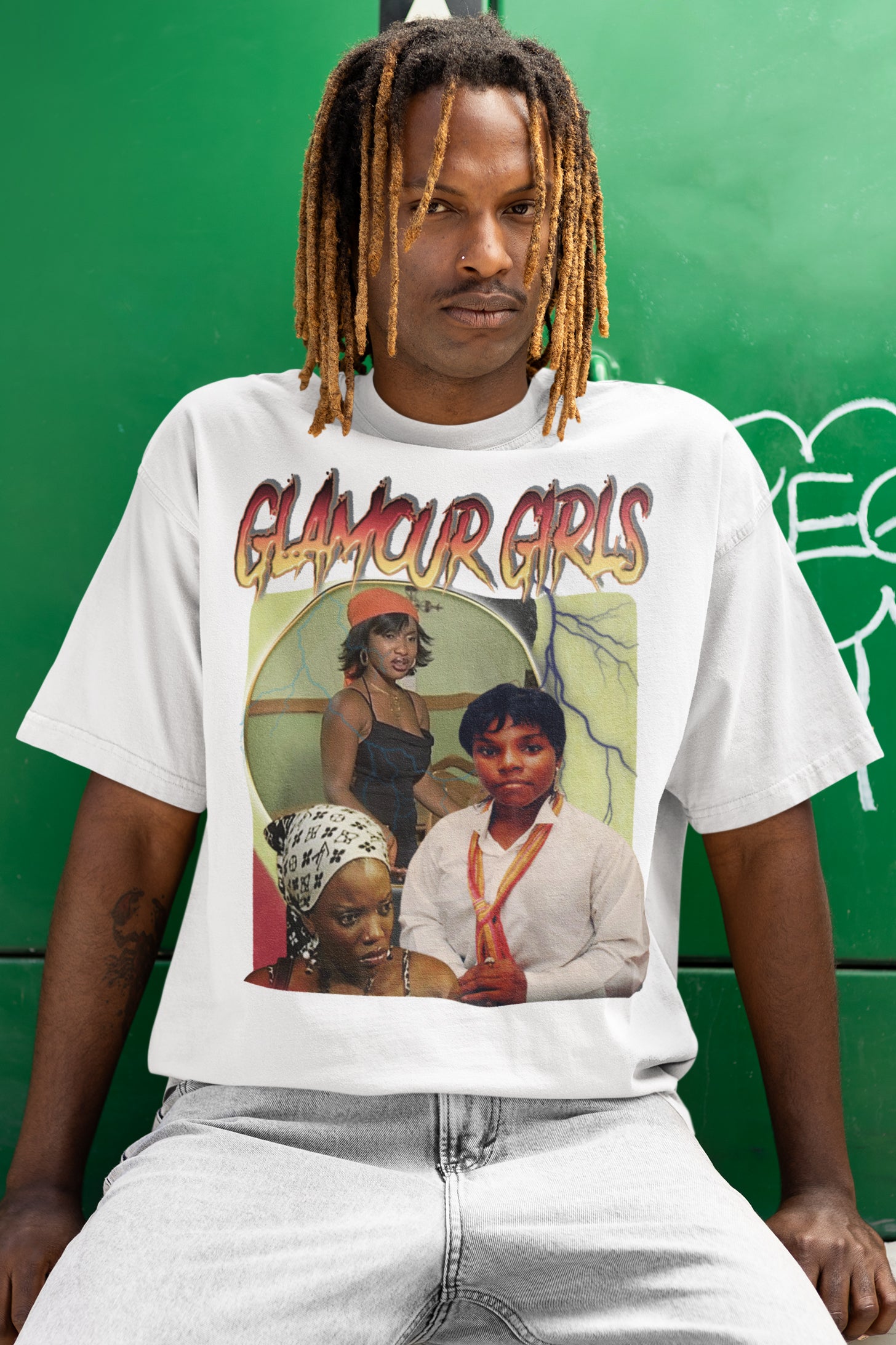 Person wearing a white t-shirt with 'Glamour Girls' graphic design against a green background